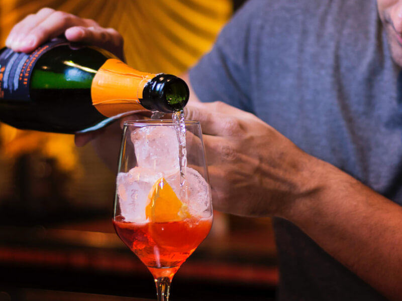 adding prosecco to an aperol spritz